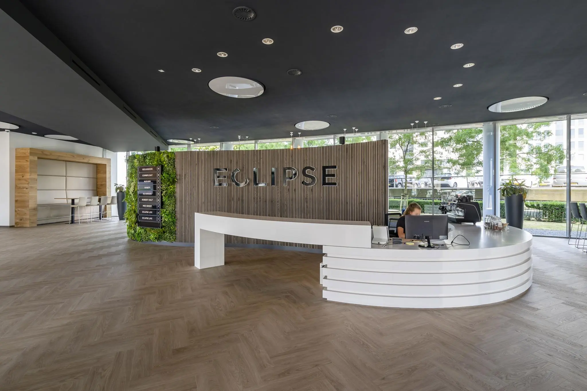 Moderne entreehal van het Eclipse-kantoor in het Rivium Quadrant met receptiebalie en groene wand.